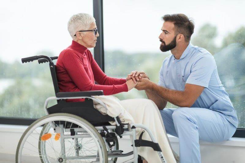 Pfleger mit älterer Dame im Rollstuhl